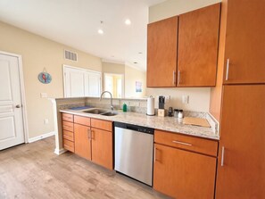 A kitchen with wooden cabinets, a dishwasher, and a granite countertop. - Modern Charlotte Apt - Pool, Gym, Game Room, & BBQ (Charlotte)