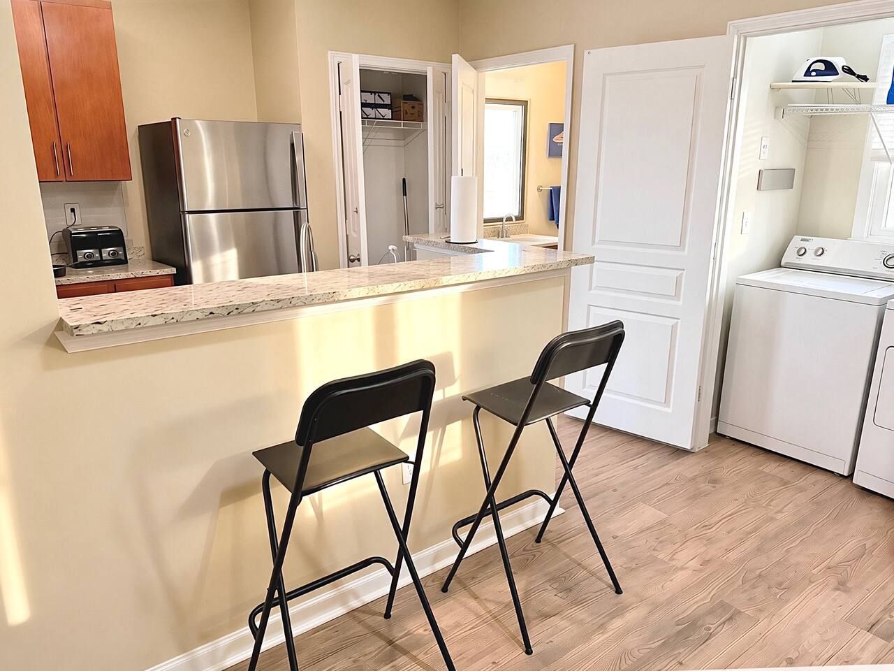 A compact kitchen with a stainless steel refrigerator, a toaster, and a white washing machine.