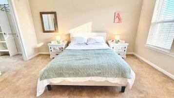 A bedroom with a bed, nightstands, a mirror, and a window.