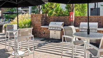 An outdoor patio with a brick wall, a grill, and outdoor seating.