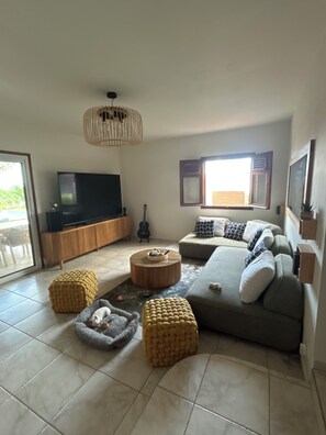 A living room with a television, sofa, ottomans, and a guitar. - Luxury home with a spa and a view of the Caribbean Sea. (Vieux-Fort)