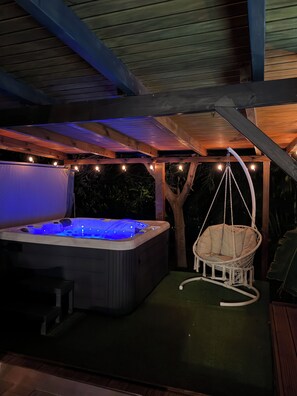 A hot tub under a wooden pergola with string lights, surrounded by greenery. - Luxury home with a spa and a view of the Caribbean Sea. (Vieux-Fort)