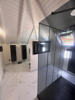 Ein Zimmer mit schrägen Wänden, einer Glastrennwand und einem Fliesenboden.