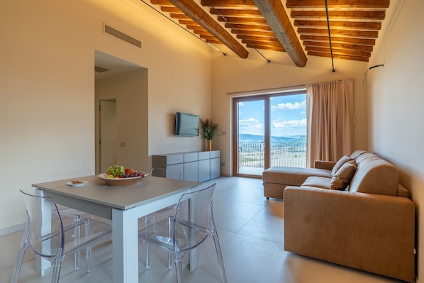 Ein moderner Wohnraum mit Essbereich, einer Couch und Blick durch eine Glastür.