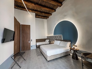 A modern bedroom with a large bed, a TV mounted on the wall, and a unique blue arch design. - Baggio Hotels - Naples Center (Naples)