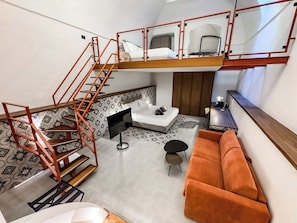 A compact living space with a loft bed, a sofa, a small table, and a staircase. - Baggio Hotels - Naples Center (Naples)
