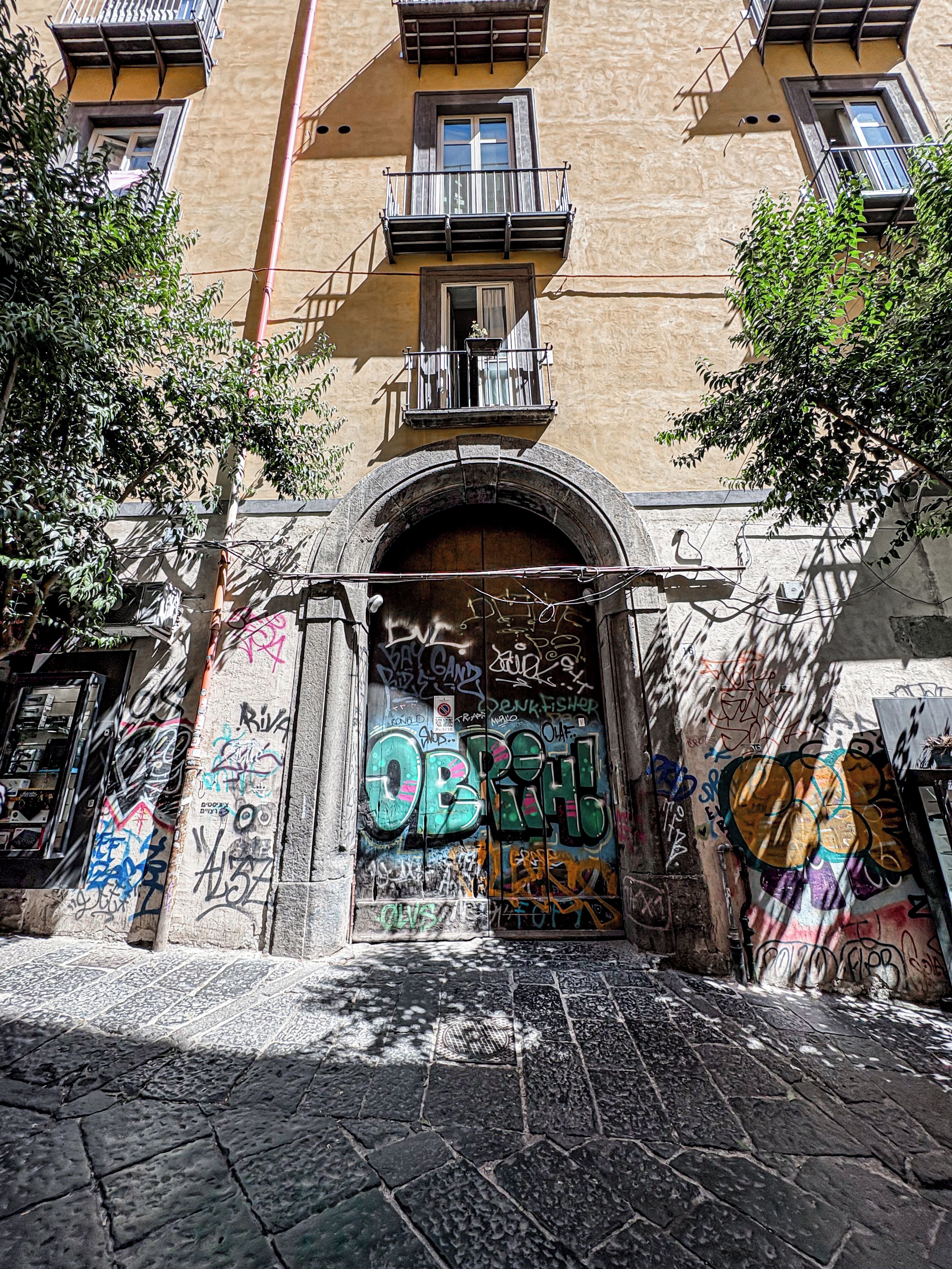 Facciata di un edificio con un ampio ingresso ad arco, numerose finestre e balconi.