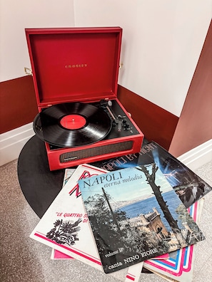 A red record player with a vinyl record and a booklet titled 'NAPOLI eterna melodia' on a black surface. - Baggio Hotels - Naples Center (Naples)