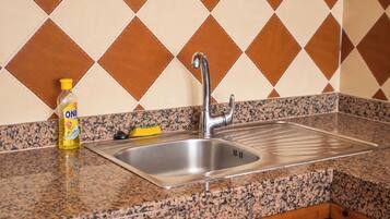 A kitchen with a stainless steel sink, granite countertop, and a bottle of dish soap.