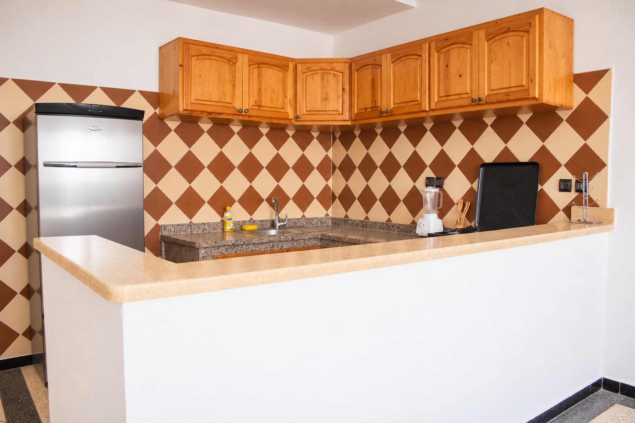 A kitchen with a built-in refrigerator, a sink, and wooden cabinets.