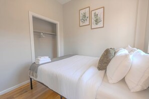 A bedroom with a bed, a wardrobe, and two framed botanical prints on the wall. - Expansive South End Studio (Boston)