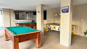 A pool table and a billiards table in a room with beige walls and a 'PROHIBIDO' sign. - Millenium Thermas Residence Condominium (Caldas Novas)