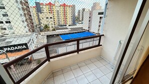 A balcony with a metal railing, a view of a parking lot, and a building with a sign that reads 'PADARIA'. - Millenium Thermas Residence Condominium (Caldas Novas)