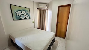 A bedroom with a bed, a painting on the wall, a door, and an air conditioning unit. - Millenium Thermas Residence Condominium (Caldas Novas)