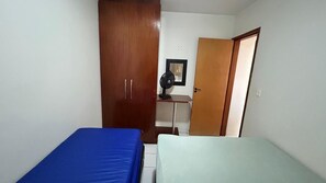 A room with two beds, a wardrobe, a desk with a chair, and a standing fan. - Millenium Thermas Residence Condominium (Caldas Novas)