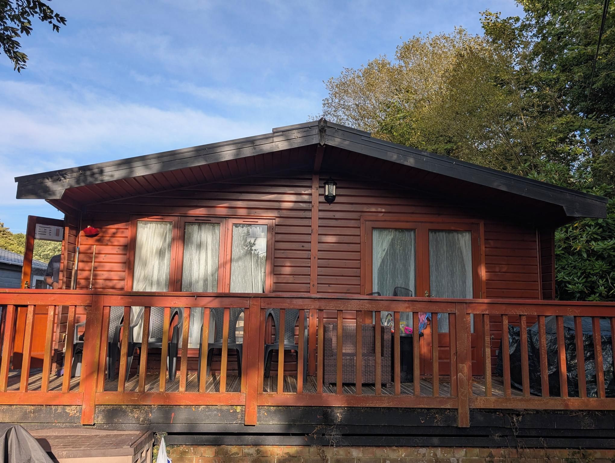 A wooden cabin with a porch, multiple windows, and a chimney.
