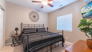 A bedroom with a bed, a ceiling fan, a wall clock, a window with blinds, and a potted plant. - Lakefront Condo + Free Slip & Elevator access (Camdenton)