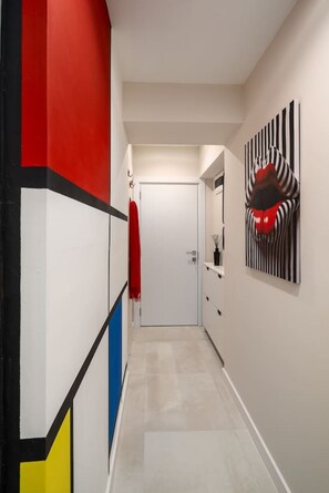 Ein Flur mit einer weißen Tür, einem roten Handtuch an der Wand und einem gestreiften Kunstwerk.