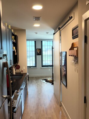 A modern kitchen with a central island, built-in appliances, and a view through large windows. - Deep Ellum Theatre Suite – Private Cinema, Skyline & City Vibes (Dallas)