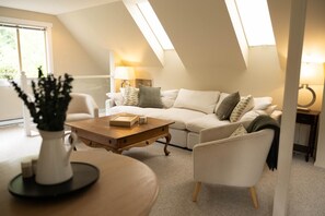 Uma sala de estar moderna com sofá, poltronas, mesa de centro e luminária.