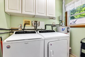 A laundry room with two Whirlpool washers, a window with a view of trees, and a water heater on the wall. - Pocono Chalet Fireplace, Loft & Resort Fun (Lake Ariel)