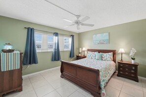 A bedroom with a bed, a nightstand, a dresser, a ceiling fan, and a window with curtains. - Great NSB Location on Intercoastal (New Smyrna Beach)