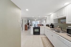A modern kitchen with white cabinets, a central island, and a built-in oven. - Great NSB Location on Intercoastal (New Smyrna Beach)