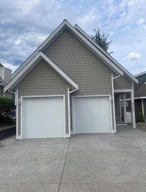 A two-car garage attached to a residential building with a gable roof and a brick exterior. - Cozy Okanagan escape between Big White & SilverStar - ski, relax & unwind! (Kelowna)