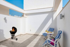 A patio with a barbecue grill, two striped lounge chairs, and a small table with a bottle and a glass. - Villa Casa Tita Mercedes by Villa Plus (Nerja)