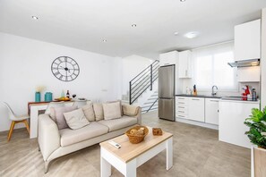 Um apartamento moderno com sala de estar, cozinha e escada.