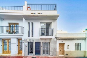 A two-story building with a balcony, a door with a sign, and a window with a metal grille. - Villa Casa Tita Mercedes by Villa Plus (Nerja)