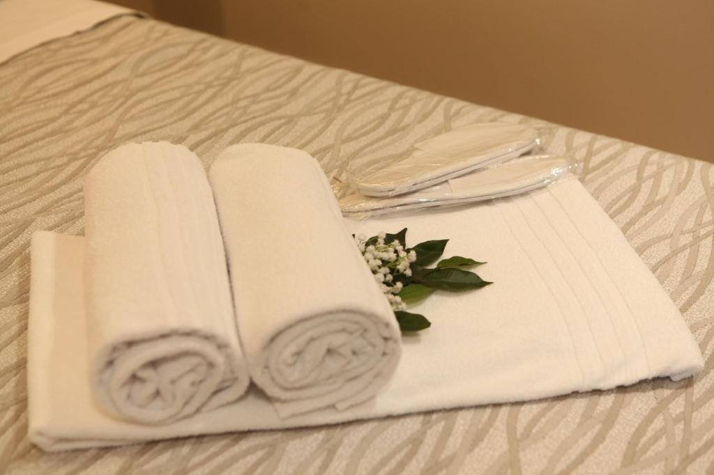 Een netjes gevouwen witte handdoek en een gevouwen witte doek op een bed met een gestreept laken.