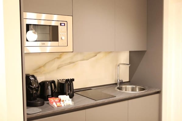 A compact kitchenette with a built-in microwave, a coffee maker, and a sink.