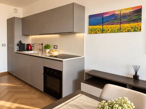 Une cuisine moderne avec des meubles gris, un four encastré et une bouilloire rouge.