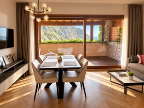 Ein modernes Wohnzimmer mit Essbereich, Fernseher und Blick auf eine gebirgige Landschaft.