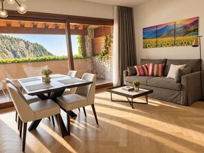 Un salon moderne comprenant un coin repas, un canapé et un tableau représentant un paysage.