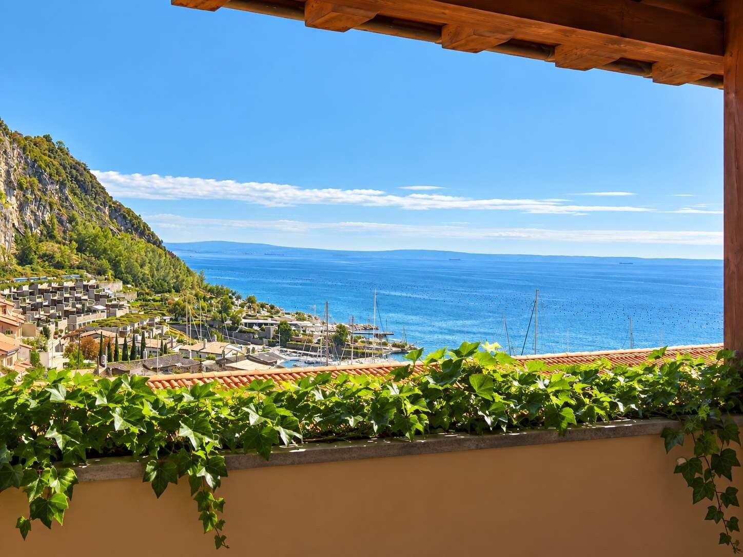A coastal town with buildings, a marina, and a clear view of the sea.
