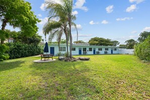 A light blue building with a flat roof, a blue door, and a small porch with two chairs. - NEW LISTING: Charming 2-Bedroom Deerfield Beach Apartment Near Beach & Shops (Deerfield Beach)