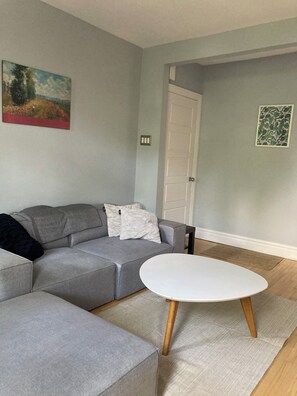 A modern living room with a grey sectional sofa, a white coffee table, and a painting on the wall. - Quiet apartment near Molson Park: two bedrooms, living room, full kitchen (Montréal)