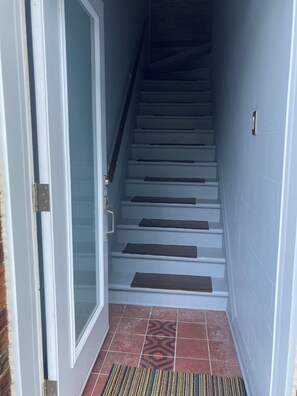 A staircase with a handrail, a door with a glass panel, and a patterned doormat. - Quiet apartment near Molson Park: two bedrooms, living room, full kitchen (Montréal)