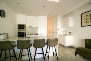 A modern kitchen with a central island, bar stools, and a dining area with a table and chairs. - FLH Vale do Lobo Delightful Terrace (Vale do Lobo)