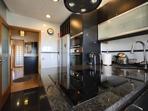 A modern kitchen with a black countertop, stainless steel appliances, and a large window. - FLH Porto Central Comfy Duplex (Porto)