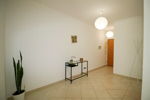 A hallway with a potted plant, a small table with a vase, and a door leading to another room. - FLH Olhão Minimalist Apartment with Balcony (Olhão)
