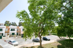 A tree-lined street with parked cars and buildings in the background. - FLH Olhão Minimalist Apartment with Balcony (Olhão)