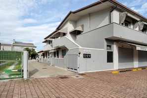 A modern building with a flat roof, a gated entrance, and a paved driveway.