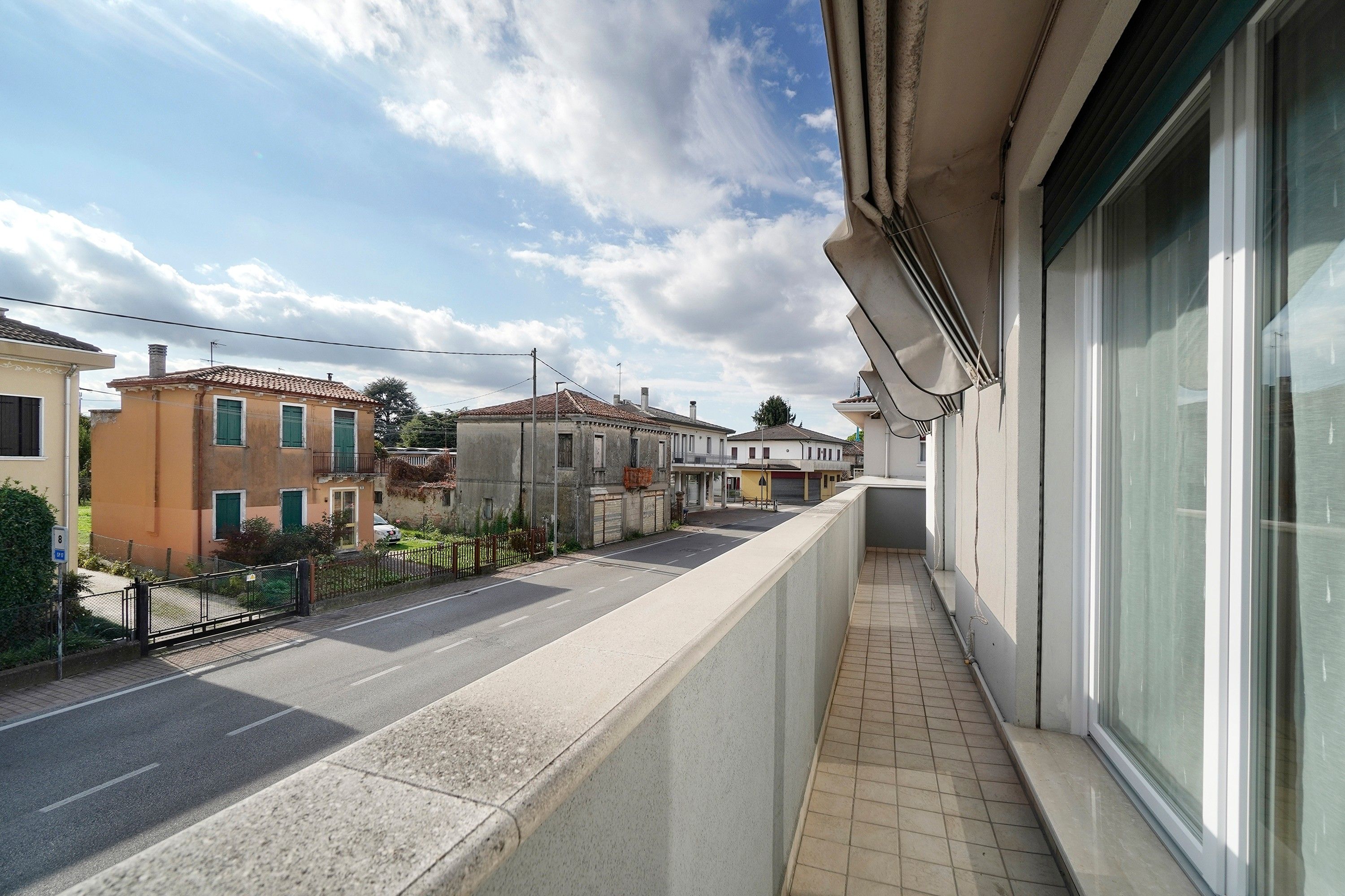 A residential street with houses, a clear sky, and a sidewalk.