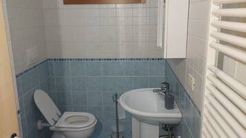 Une petite salle de bain comprenant des toilettes, un bidet, un lavabo et une fenêtre située au-dessus des toilettes.