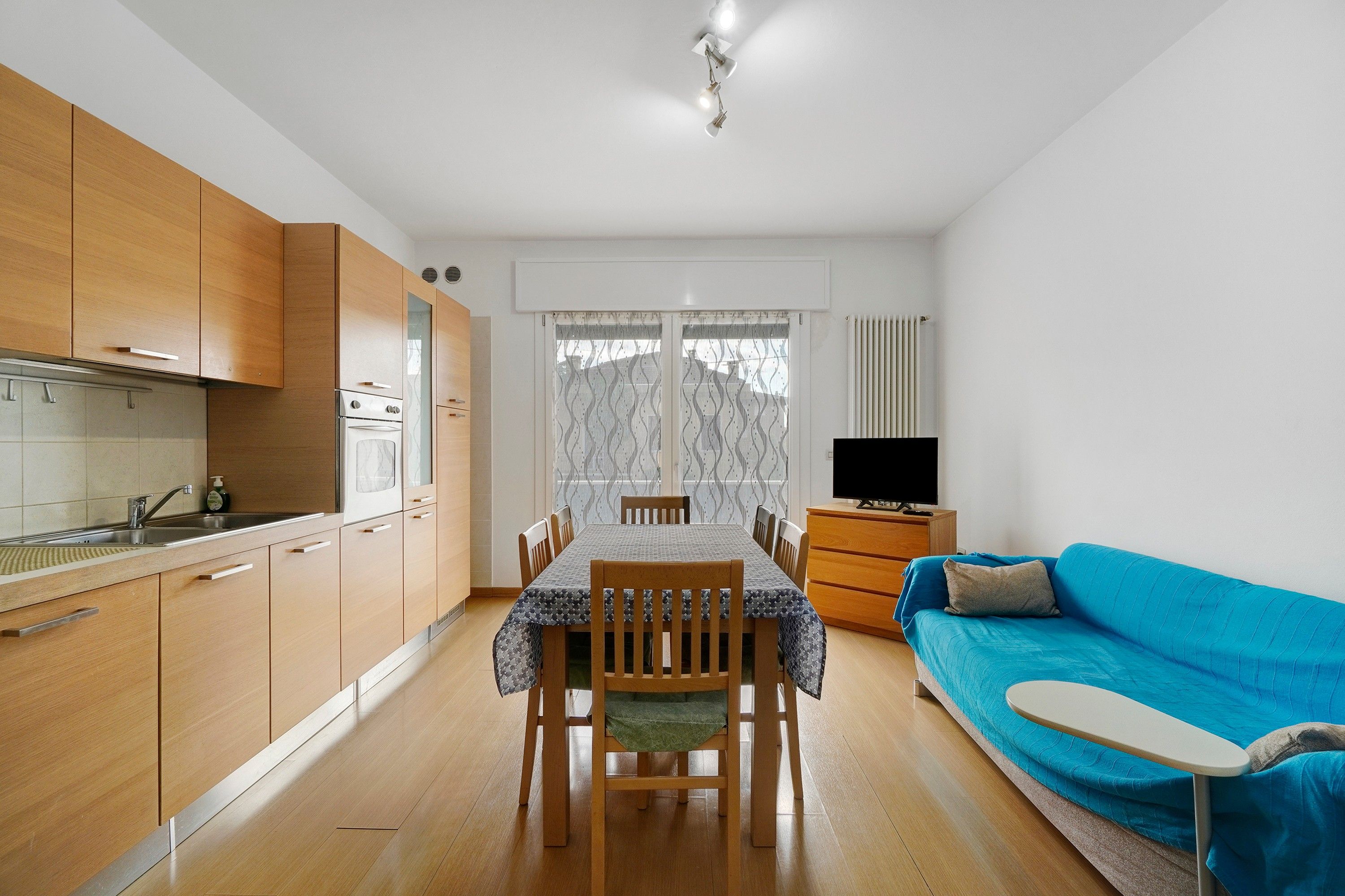 Een compacte woonruimte met een kitchenette, eethoek en een bank.
