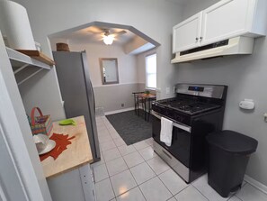 A compact kitchen with a stove, refrigerator, and white cabinets. - Cozy Allen Park Bungalow (Allen Park)