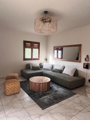 Una sala moderna con un sofá modular, una mesa de centro redonda y un espejo grande.